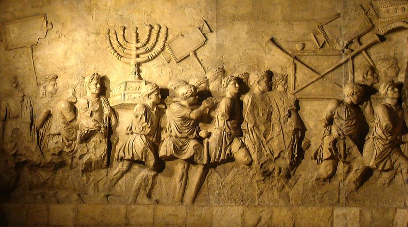 Stone relief from the Arch of Titus depicting Roman soldiers carrying the seven-branched menorah and other Temple treasures in triumphal procession after the 70 CE sack of Jerusalem.