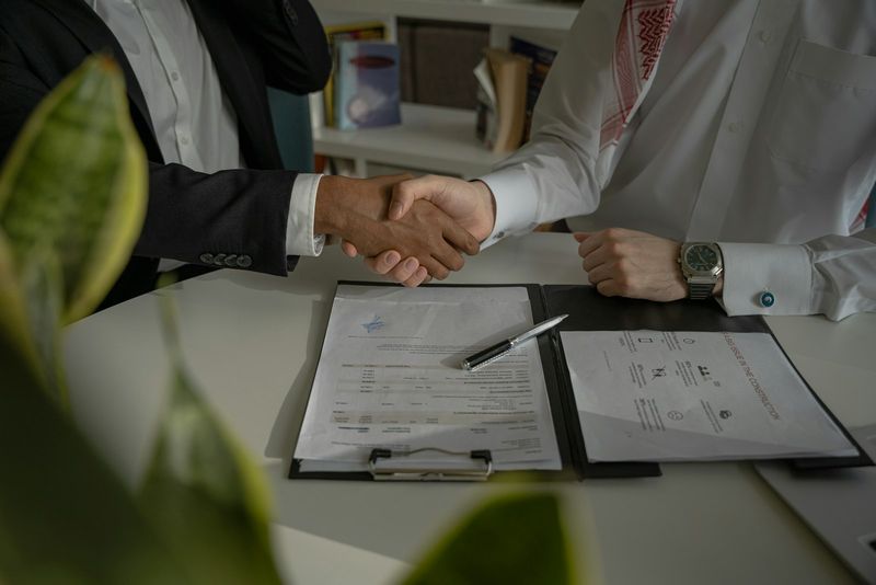 Two businesspeople shaking hands over a signed contract