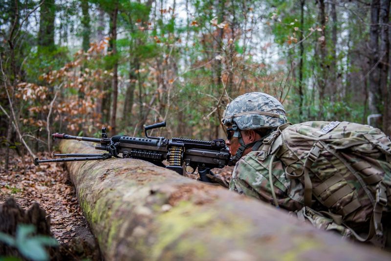 A soldier in the prone position aiming an M4 rifle during training at Fort Benning.