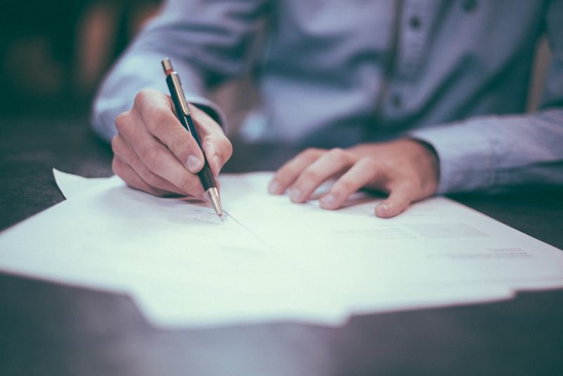A person signing legal estate planning documents with a pen